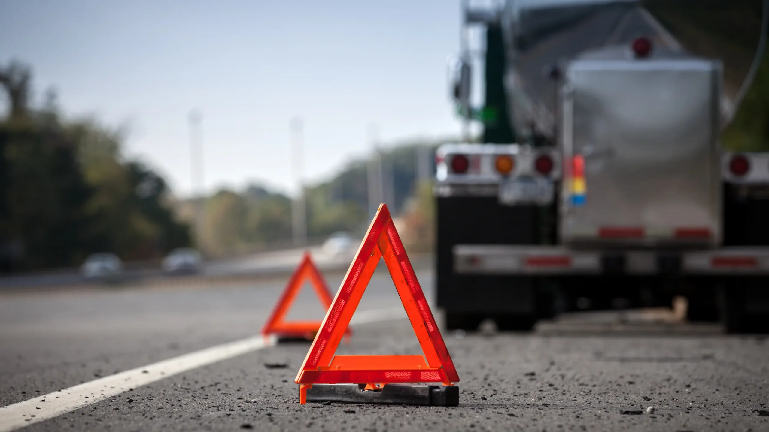 Hazard cones line the side of a street to warn of a stopped truck.